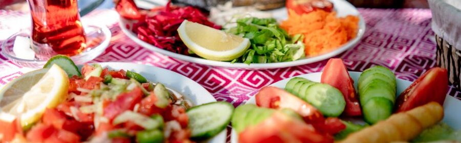 Close-up of a Mediterranean meal with grilled fish, fresh salad, and tea on a restaurant table.